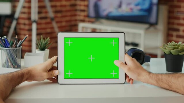 Male student looking at horizontal green screen on display, working with digital gadget at home. Using isolated chroma key template and blank copy space with mock up on tablet. Close up.