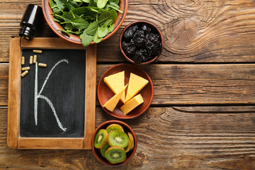 Chalkboard with letter K, bottle of pills and healthy products on wooden background