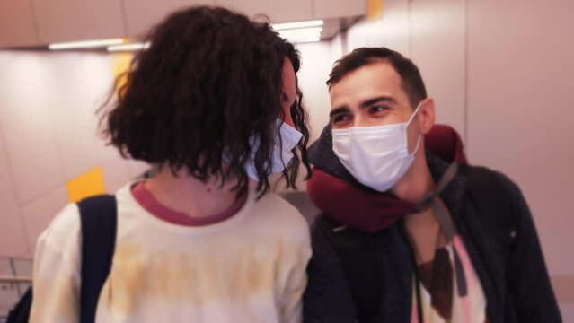 Portrait of two caucasian people in facial masks riding on escalator in airport terminal. Man and woman are smiling and waiting for their vacations in spite of coronavirus pandemic and restrictions
