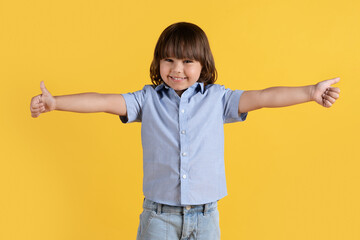 Sincere childish approval. Cute happy little boy showing thumbs up gesture with both outstretched hands and smiling