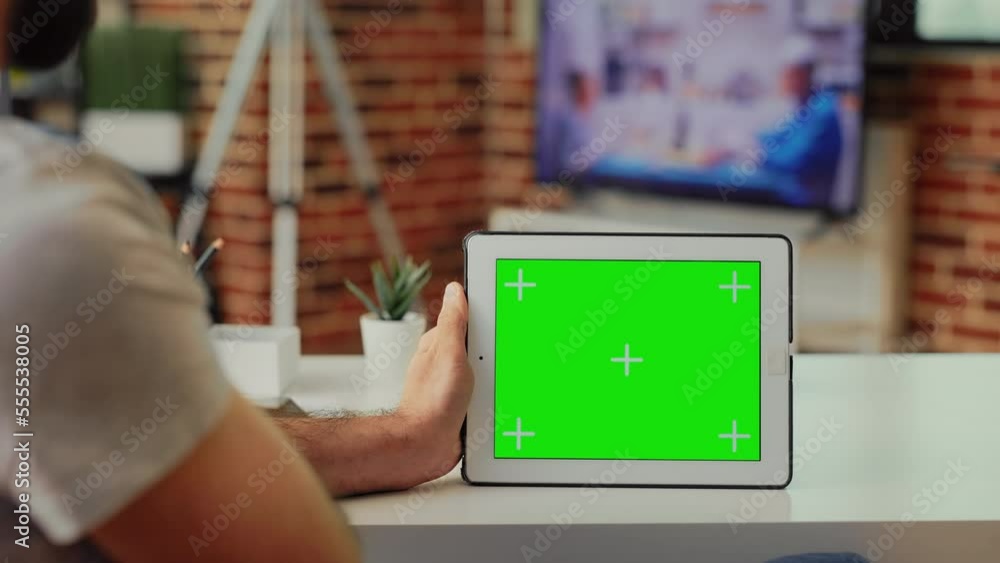 Poster young adult working with horizontal greenscreen on digital tablet, analyzing blank mockup display an