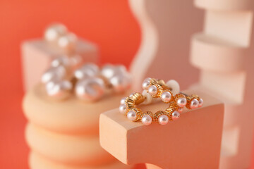 Stand with pearl earrings on color background, closeup