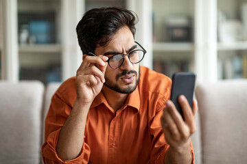 Confused arab man feeling shocked, received bad message on cellphone