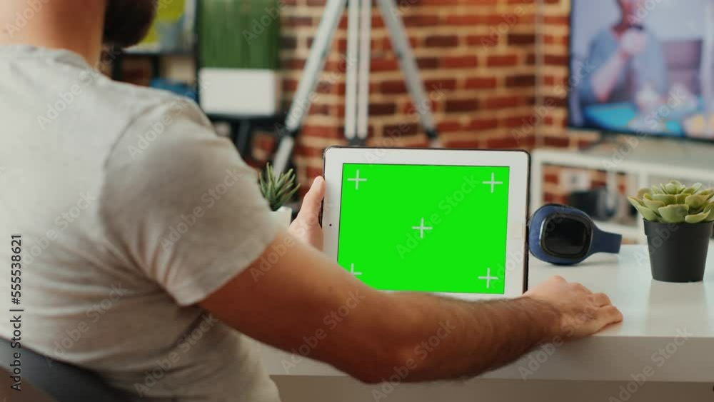 Aufkleber young man holding modern device with horizontal greenscreen template in living room, sitting at desk
