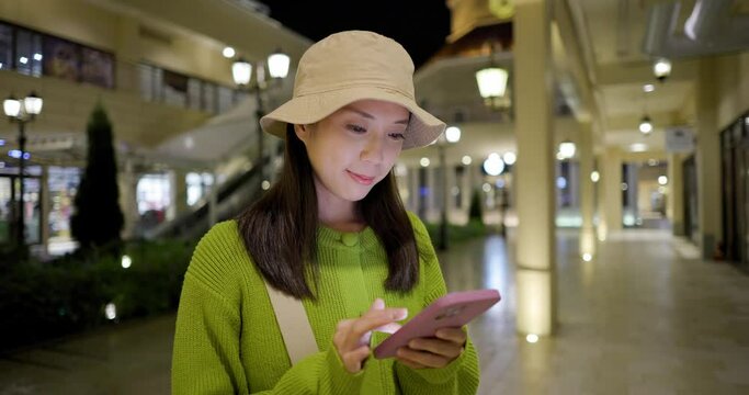 Woman use mobile phone in shopping mall at night