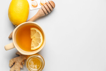 Cup of tea, pills for sore throat, lemon, ginger and honey on light background