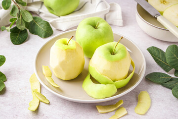 Plate with fresh juicy apples and peel on light table