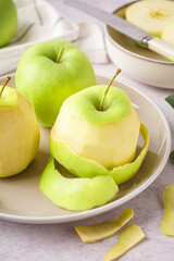 Plate with fresh juicy apples and peel on light table, closeup