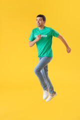Fototapeta na wymiar Young volunteer jumping on yellow background