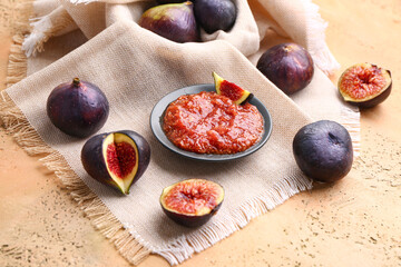 Fresh figs and plate of puree on color background