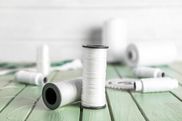 White thread spools on color wooden table