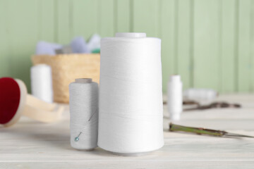 White thread spools on light wooden table