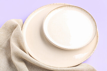 White plates and napkin on lilac background