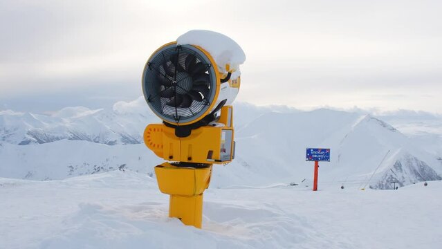 Yellow snow cannon under snow in Gudauri ski resort in snowy mountains after fresh snow fall. Good snow situation and fake snow technology