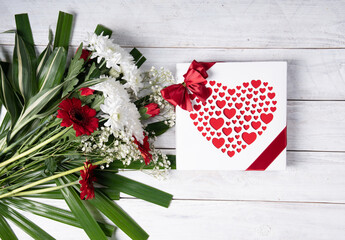 Valentine's day gift, red heart praline box and flower bouquet on white table