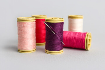 Thread spools with needle on grey background
