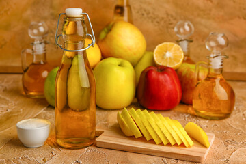 Bottle of apple cider vinegar, sugar and fruits on color background