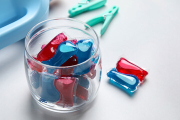 Jar with laundry detergents and clothespins on grey background