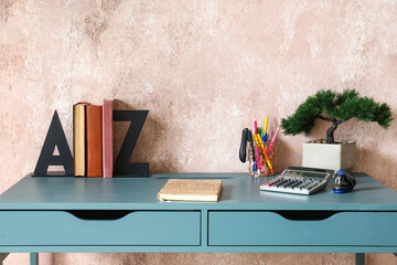 Workplace with bookend and bonsai near pink wall
