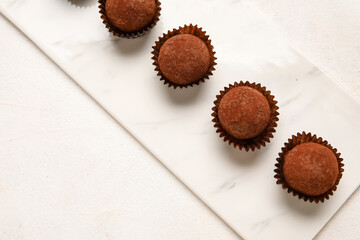 Board with chocolate truffles on white background