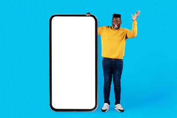 Excited Young Black Man Standing Near Huge Black Smartphone With White Screen