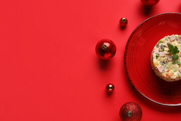Composition with plate of tasty Olivier salad and Christmas balls on red background