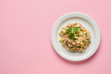 Plate with tasty Olivier salad on pink background