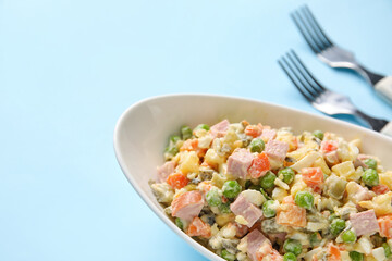 Bowl of tasty Olivier salad on color background, closeup