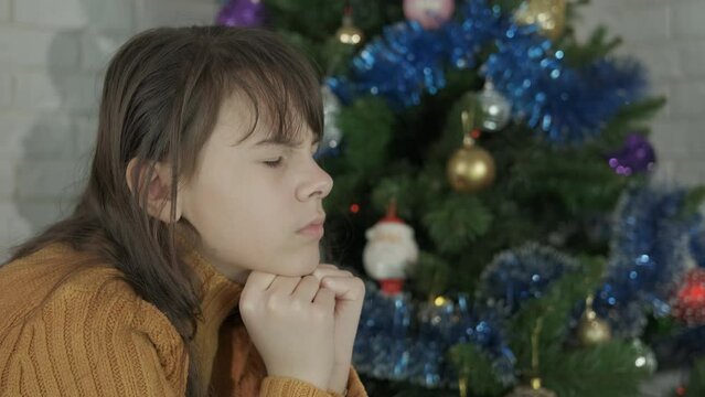 Upset girl at Christmas party at home. Upset teenager pas her holiday in the Christmas decorated room.