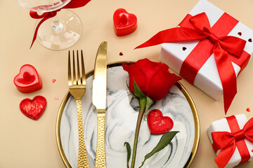 Fototapeta na wymiar Table setting for Valentine's Day with red rose and gifts on beige background