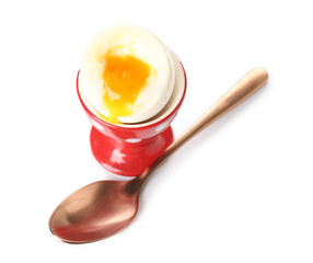 Cup with soft boiled egg and spoon on white background