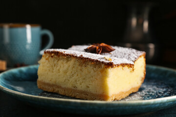 Blue plate with piece of cheese pie and anise on table against black background