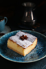Blue plate with piece of cheese pie and anise on black table