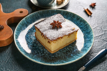 Blue plate with piece of cheese pie and anise on black table