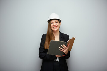 Woman in black suit and safety helmet holding open book.