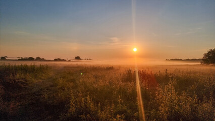 classic summer morning sunrise in meadow. autumn landscape with sunrise and fog