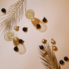 Flat lay- Golden background with New Year decorations, palm leaves and champagne glasses.