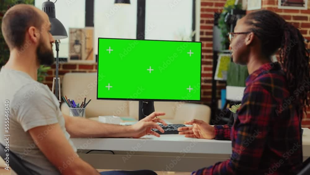 Poster diverse team working on computer with greenscreen at desk, using monitor to examine isolated display
