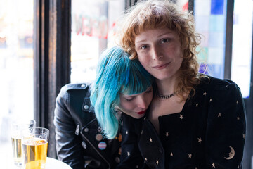 unconventional lesbian couple embrace in bar - obrazy, fototapety, plakaty