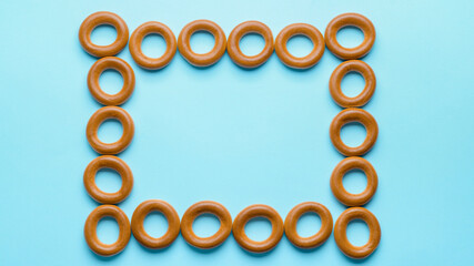 Frame made of tasty dry bagels (sushki) on light blue background, flat lay. Space for text