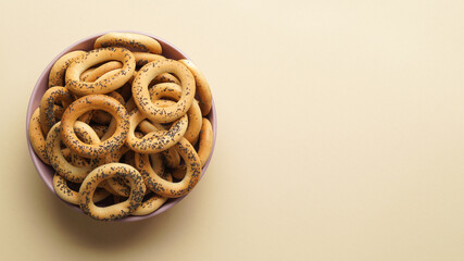 Bowl with delicious ring shaped Sushki (dry bagels) on beige background, top view. Space for text