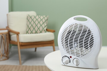 Electric fan heater on white table indoors. Space for text