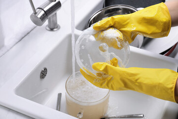 Woman washing dirty dishes in kitchen sink, closeup