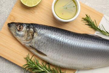 Wooden board with salted herring, lime, oil and rosemary on grey table, top view