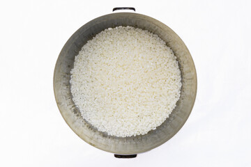 Pan with white rice inside, top view, on a white background. Uncooked food, kitchen tools