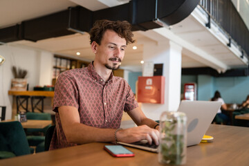 One young adult caucasian man work remote from cafe on laptop computer