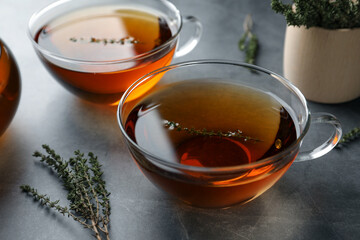 Aromatic herbal tea with thyme on grey table