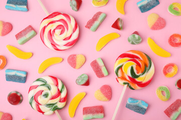 Many different jelly candies and lollipops on pink background, flat lay