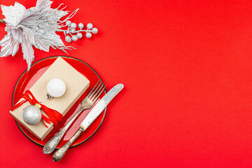 Christmas table setting with a festive gift box in red and silver colors. New Year background