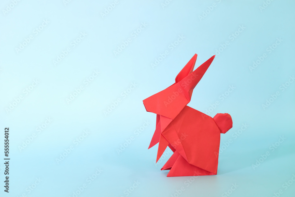 Wall mural red rabbit or bunny origami isolated in blue background. chinese new year of the rabbit and easter c